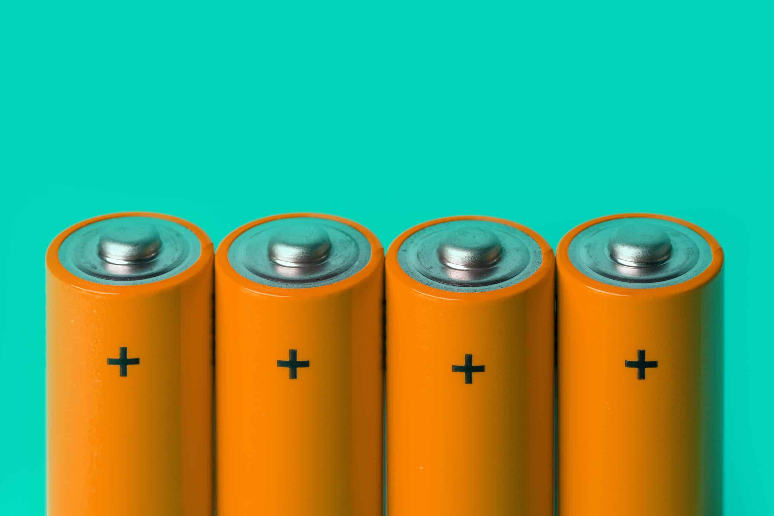 Four Orange Batteries On Green Background