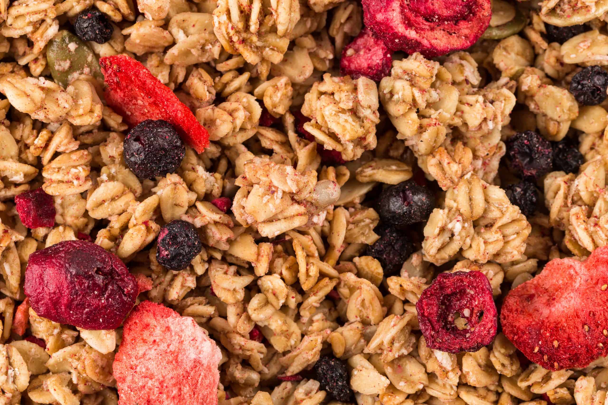 Muesli cereals close up background with  raisins, oat and wheat flakes, fruits, strawberry, cranberry, cherry pieces