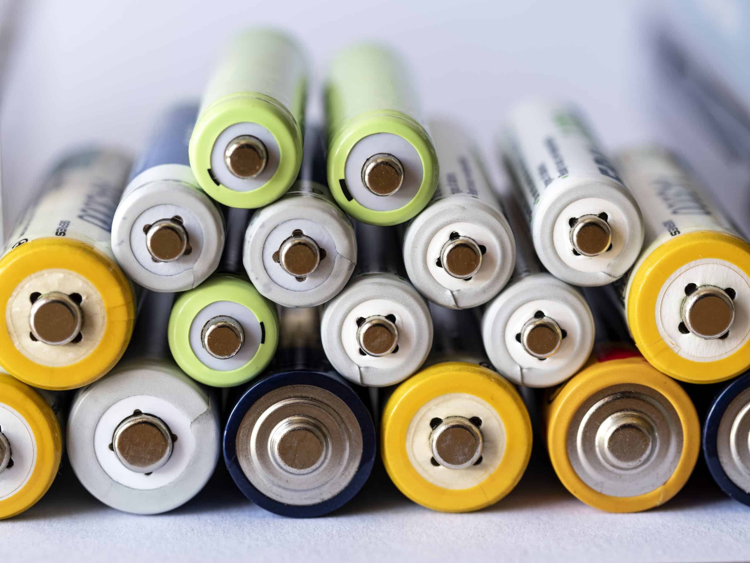 Pile of rechargeable Ni-MH batteries on white background.