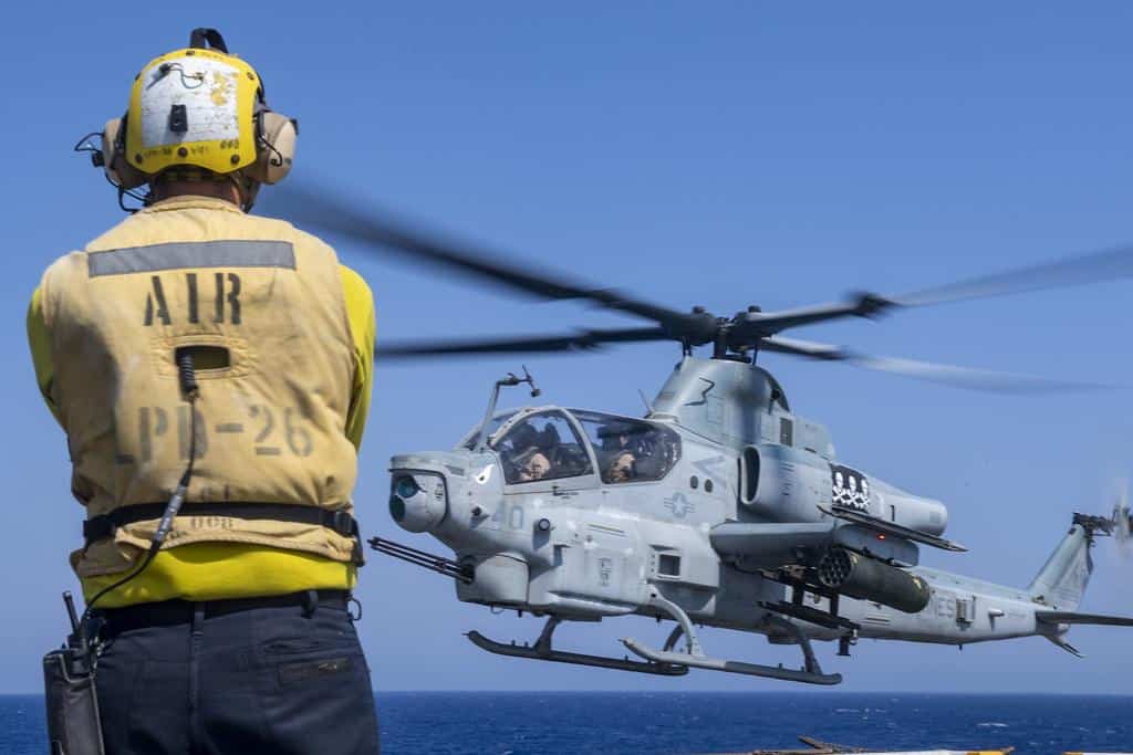 A Sailor signals AH-1Z Viper helicopter pilots during exercise Eager Lion 2019. by Official U.S. Navy Imagery