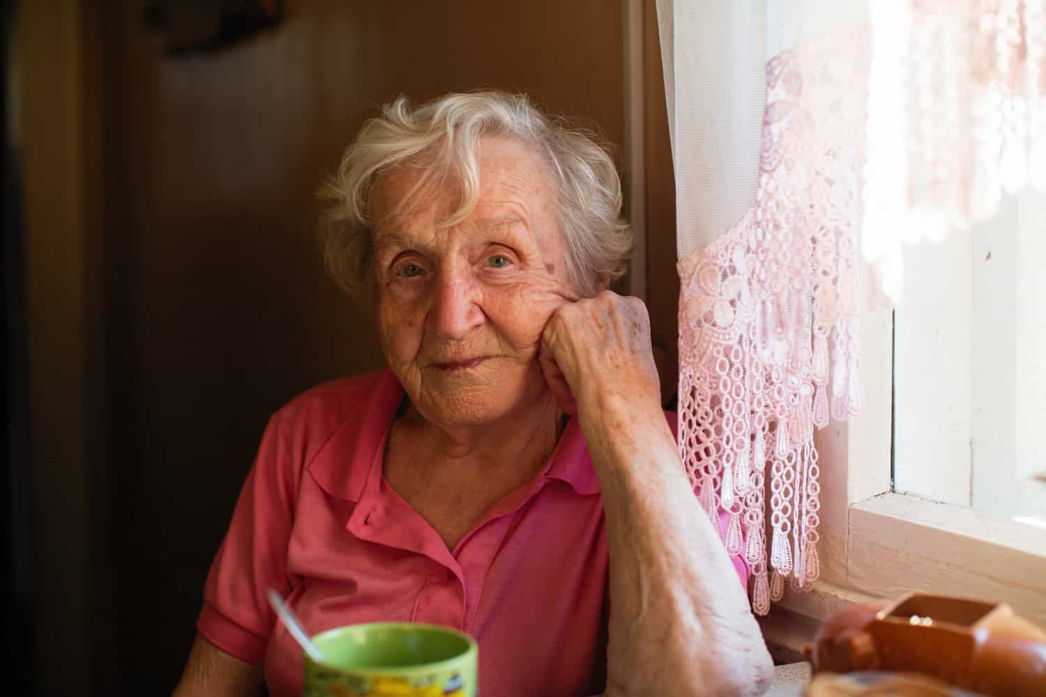 Portrait of elderly woman sitting at the table in her home.