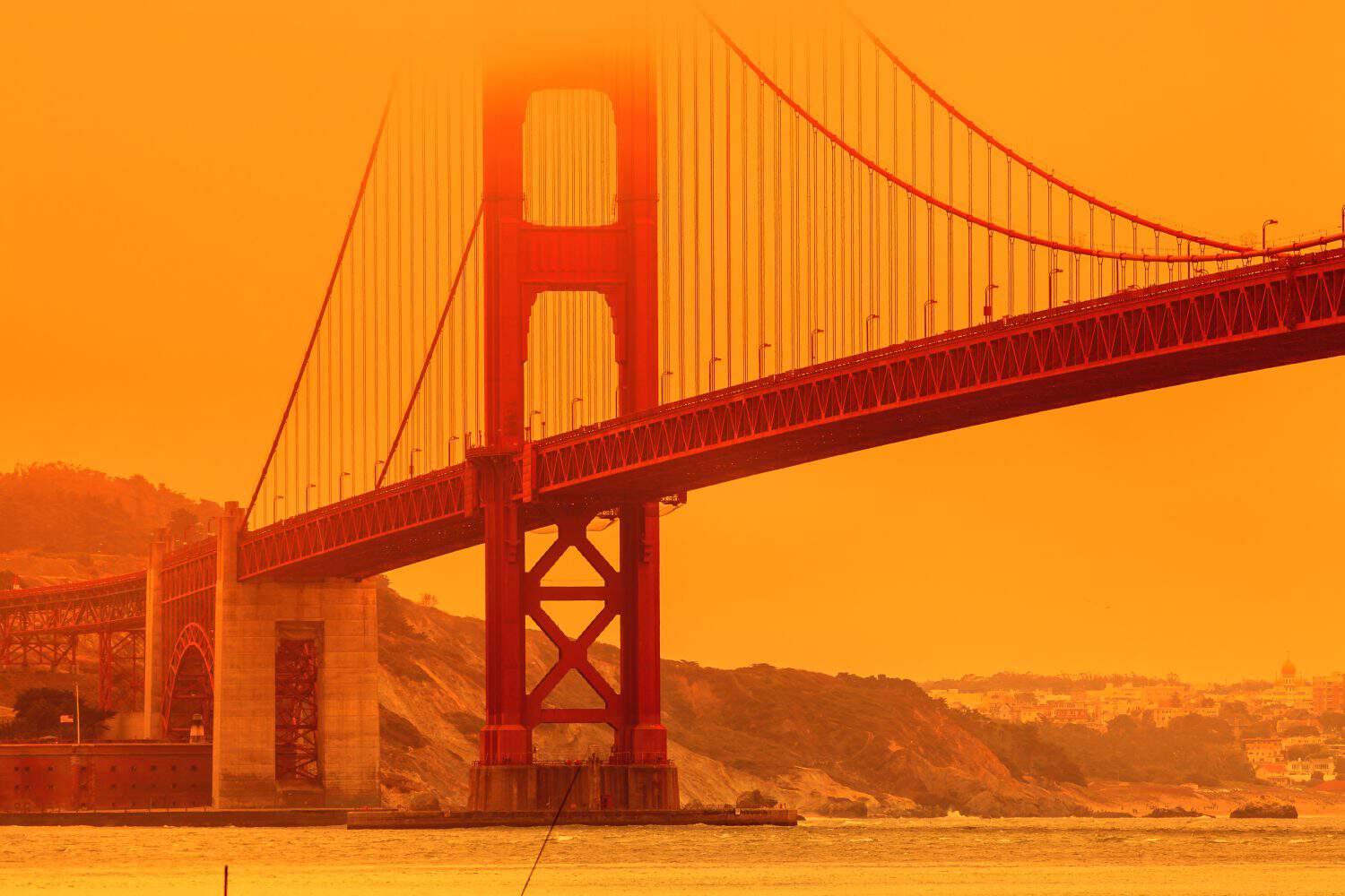 Composition about wildfires and climate change concept. Bottom view of smoky orange sky on Golden Gate bridge of San Francisco city from lime point. California fires in United States.