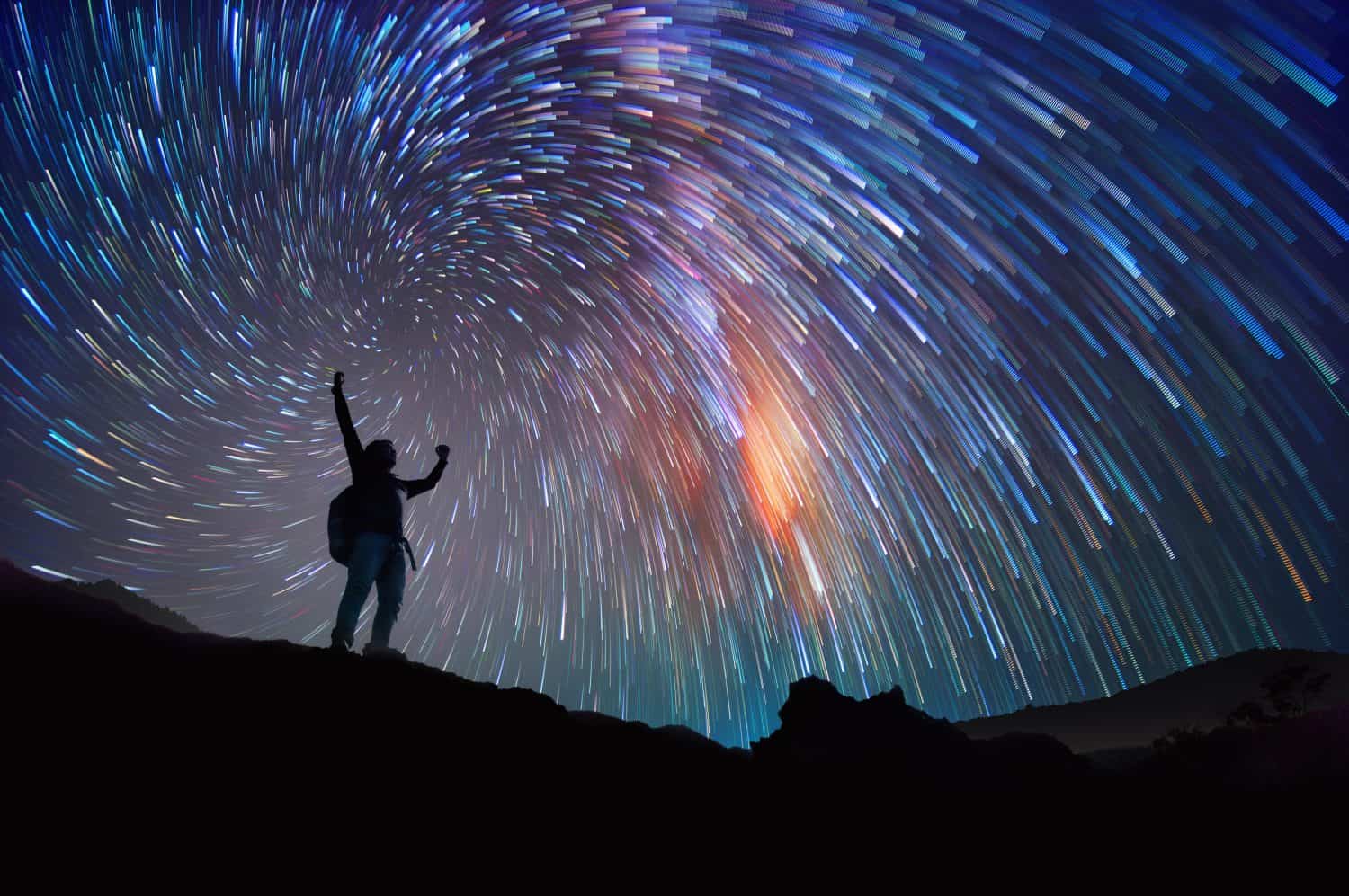 Landscape with Milky Way. Night sky with stars and silhouette of a standing happy man on the mountain, Success or winner, leader concept.