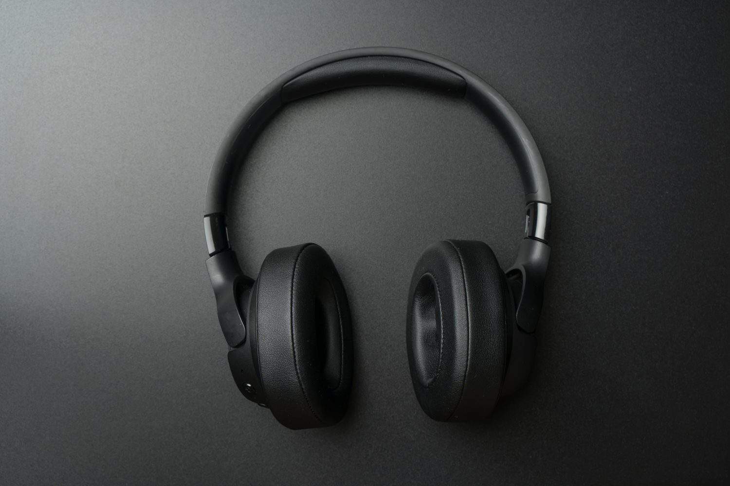 Headphones on a black background. Stylish studio headphones for listening to music, sounds, radio and podcasts lie on an empty dark table.