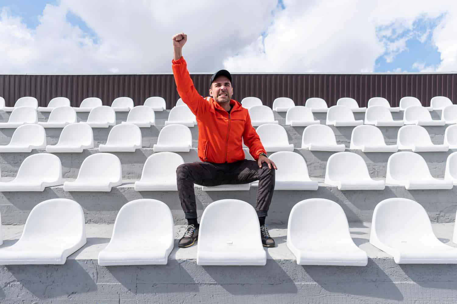 there is only one person sitting on the grandstand. He sits without a mask and looks in front of him. Quarantine.