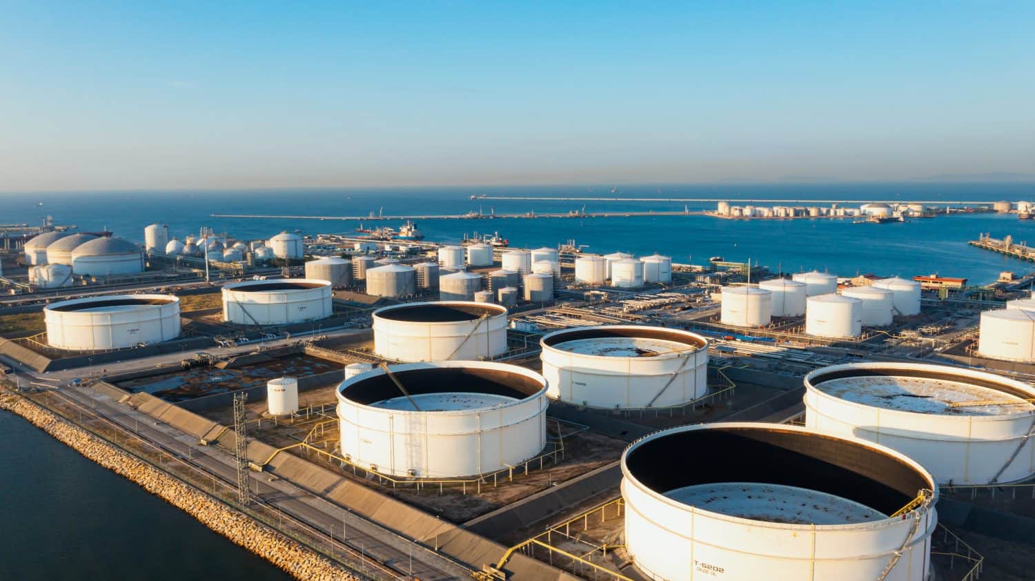 Aerial top view of White oil tank storage chemical petroleum petrochemical refinery product at oil terminal. Oil terminal storage tank in deep seaport for the international order concept.