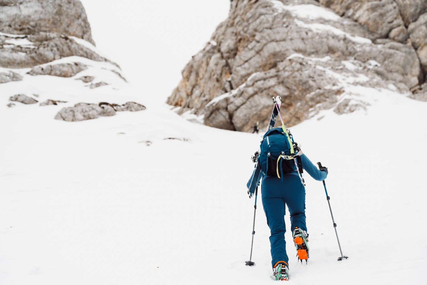 One lonely ski tourer climbing up the snowy mountain, view from behind