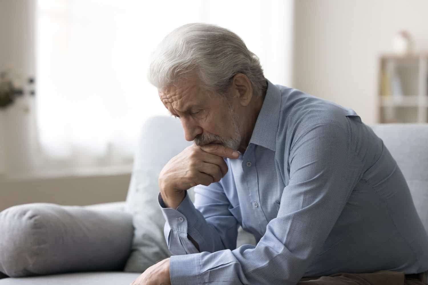 Sad lonely grey haired old man thinking on geriatric health problems, bored retirement at home, feeling sick, tired, suffering from depression, memory loss, mental disorder