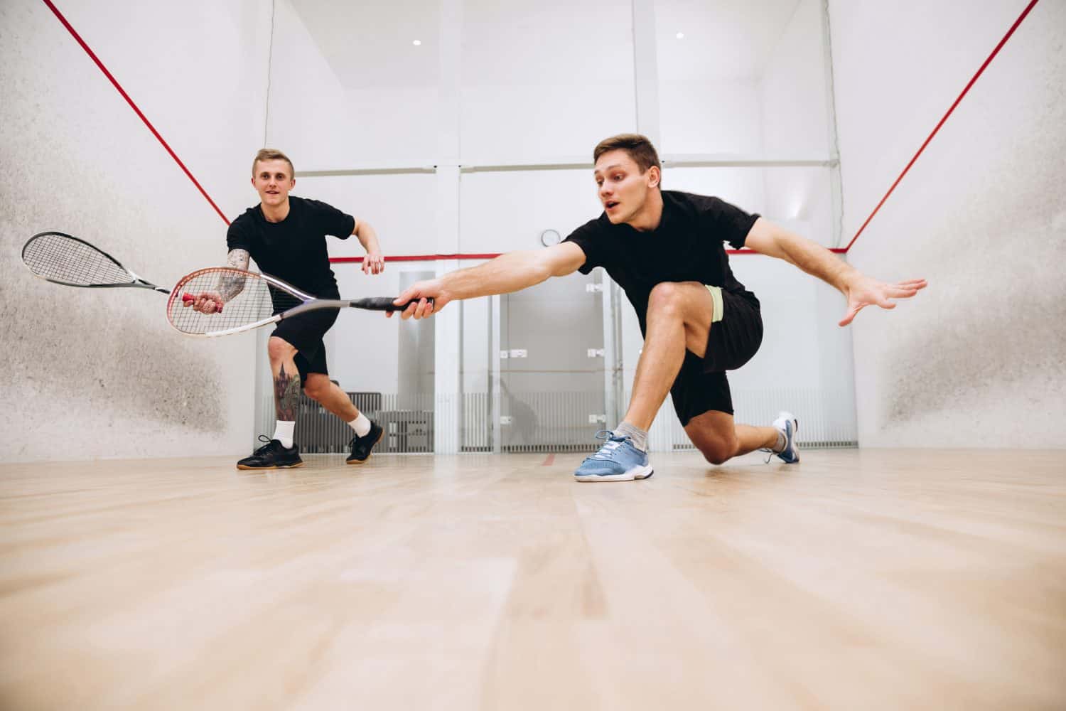Scoring a goal. Two young sportive boys training together, playing squash isolated over sport studio background. Concept of active life, team game, energy, sport, competition. Copy space for ad