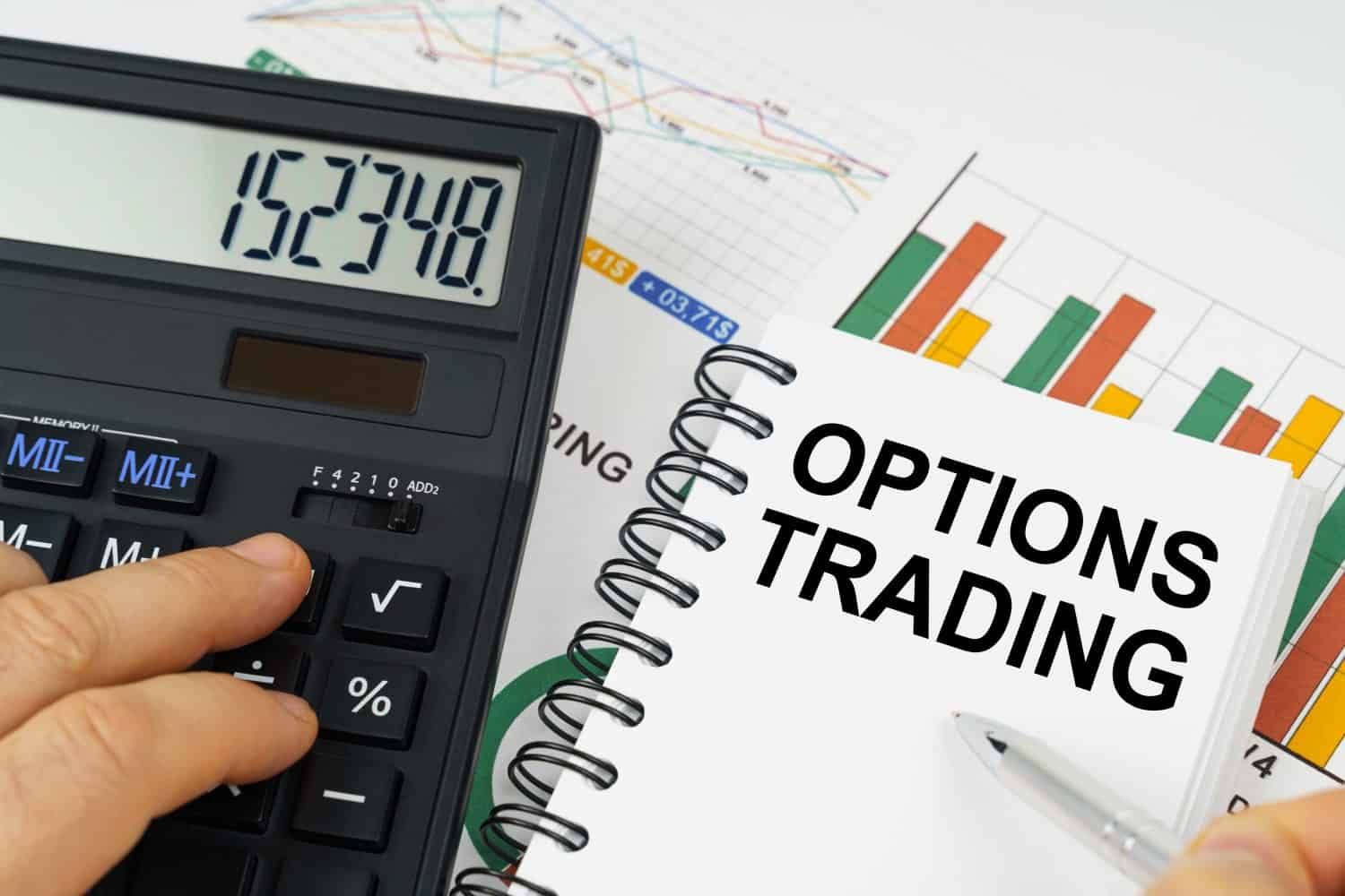 Business concept. On the table there is a calculator, reports with graphs and a notepad with the inscription - Options trading