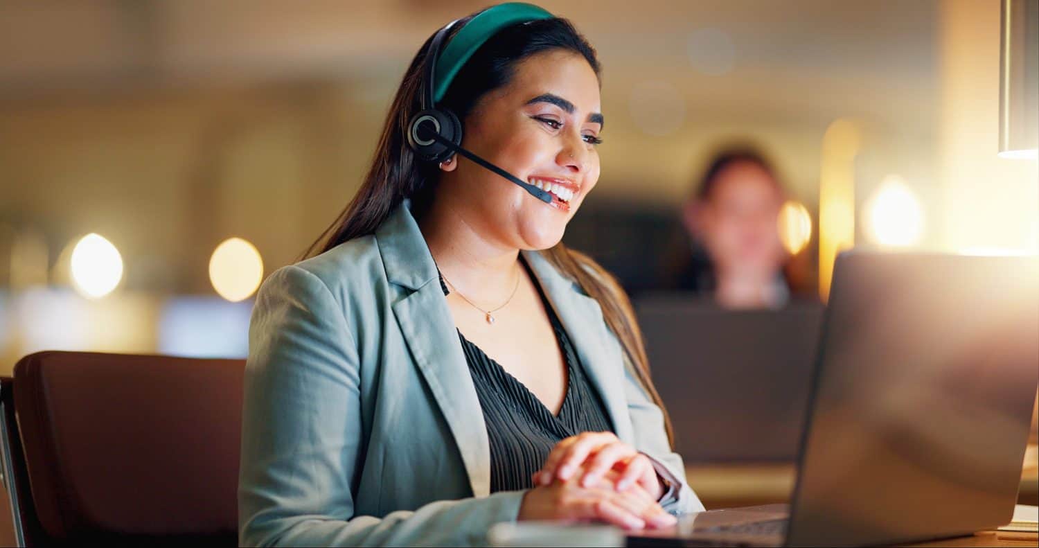 Happy woman, call center and communication with headset at night in office for customer service, lead generation. Person, CRM and laptop with faq for telecom support, contact and telemarketing advice