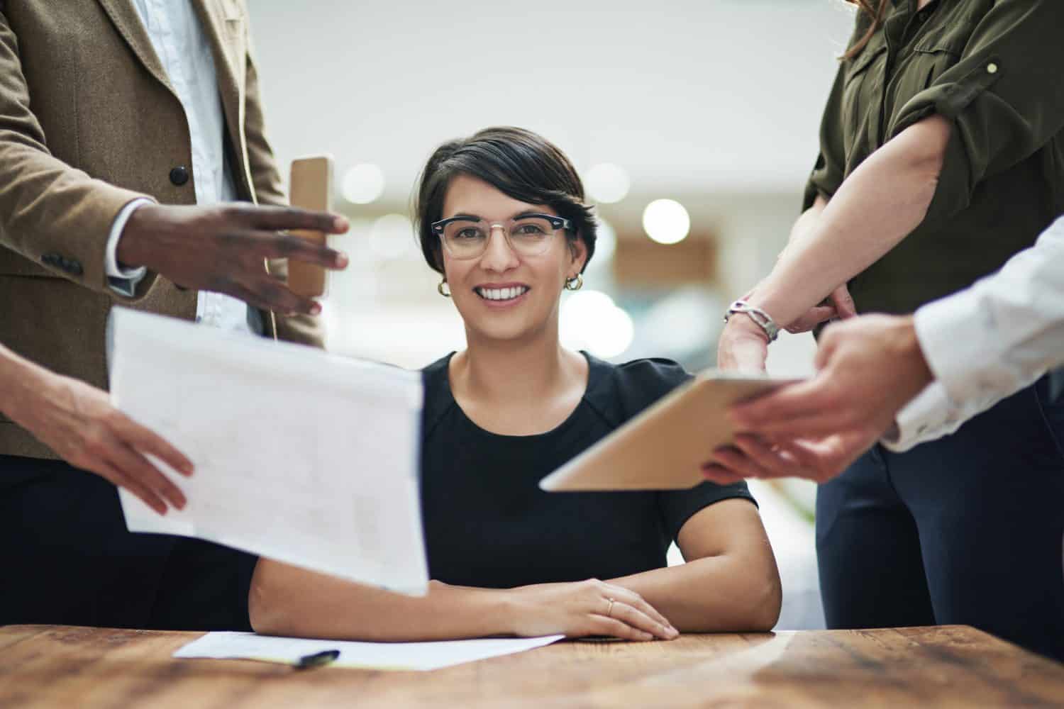 Business woman, chaos and colleagues in portrait with documents for crisis in workplace or calm in stress. Female person, coworkers and smile for teamwork, mentorship and leadership in office