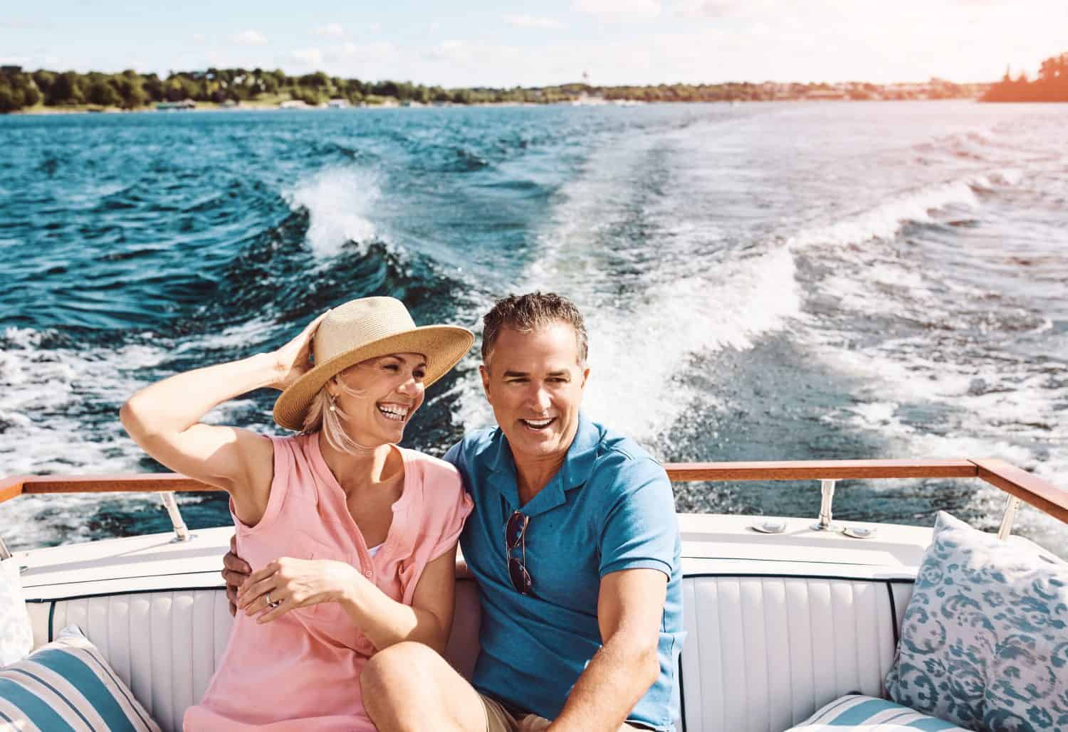 Mature couple, hug and boat cruise for holiday, travel or retirement on ocean sailing with relax. Man, woman and happy on luxury yacht at sea for love, vacation or tropical adventure by Bahamas