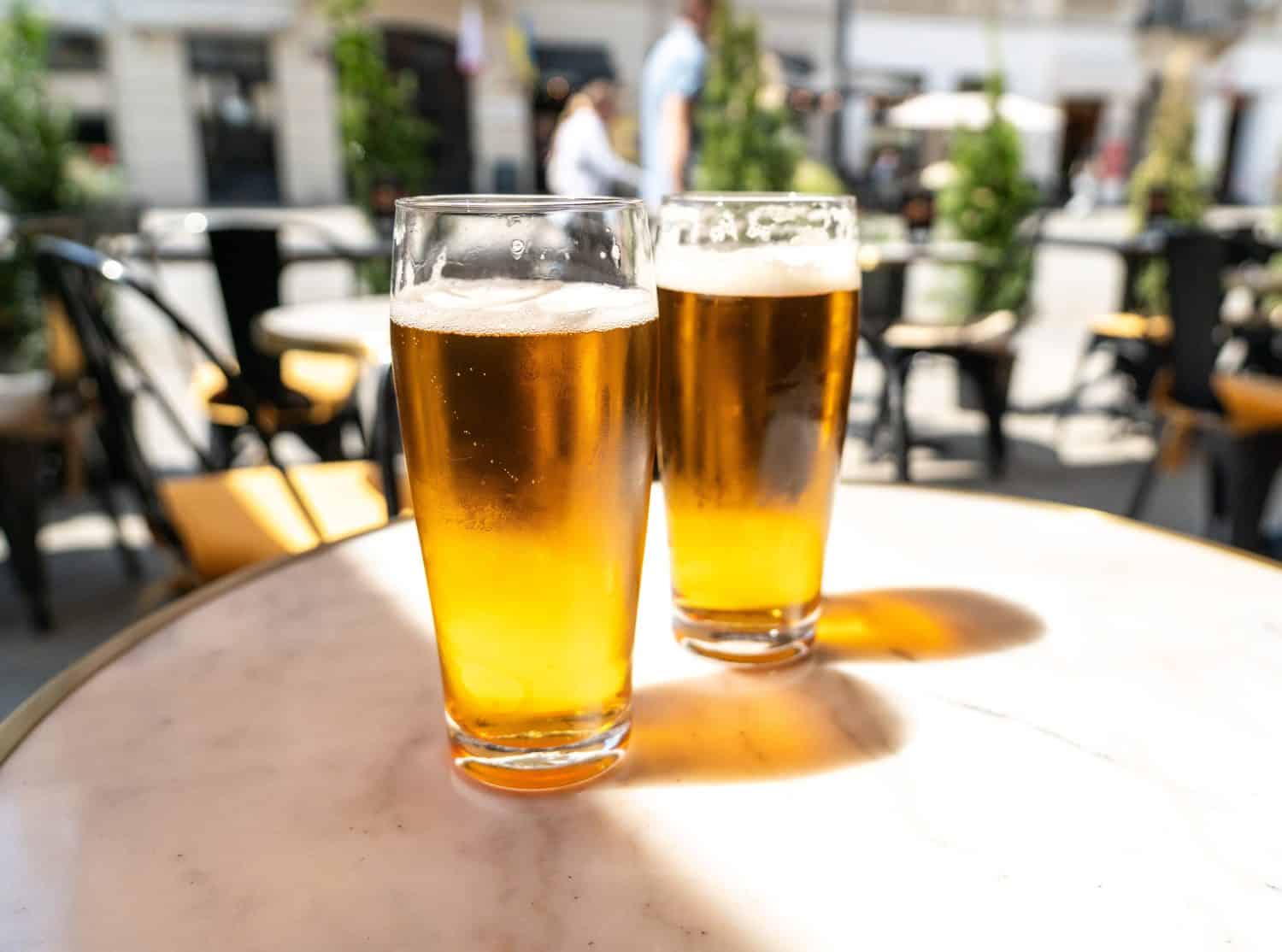 Beer glass in sunny day, cold pint glass with remaining beer on outdoor table, cool condensation and golden liquid, summer leisure and relaxation, highlighting beverage enjoyment