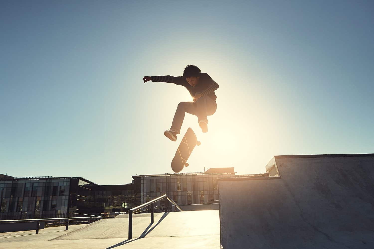 Skateboard, man and jumping in urban skate park with trick and training in Los Angeles with speed. Sunshine, deck and skater in the city with balance, skating competition and fun board flip by ramp