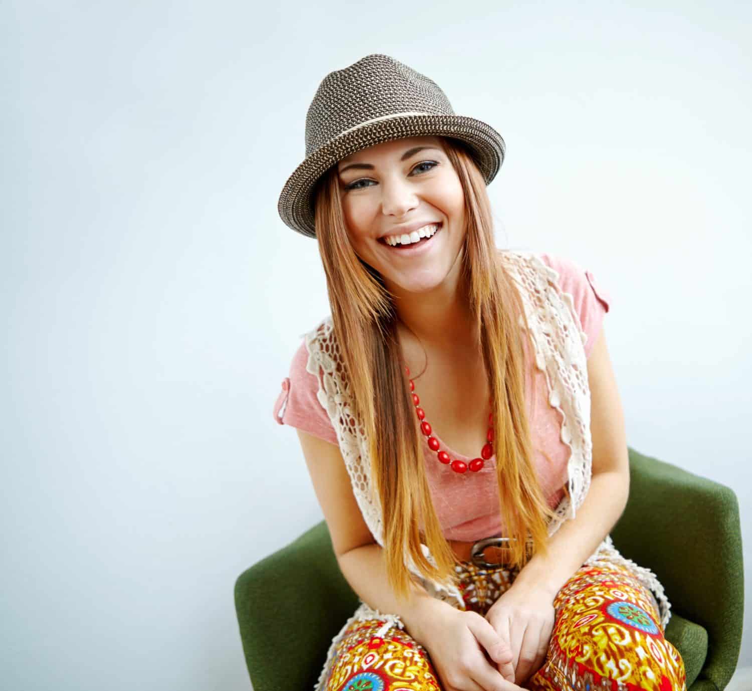 Happy woman, vintage fashion and home portrait, confidence and quirky style on white background. Female person, funky clothes and laughing on mockup space, proud hipster and relax on chair in lounge