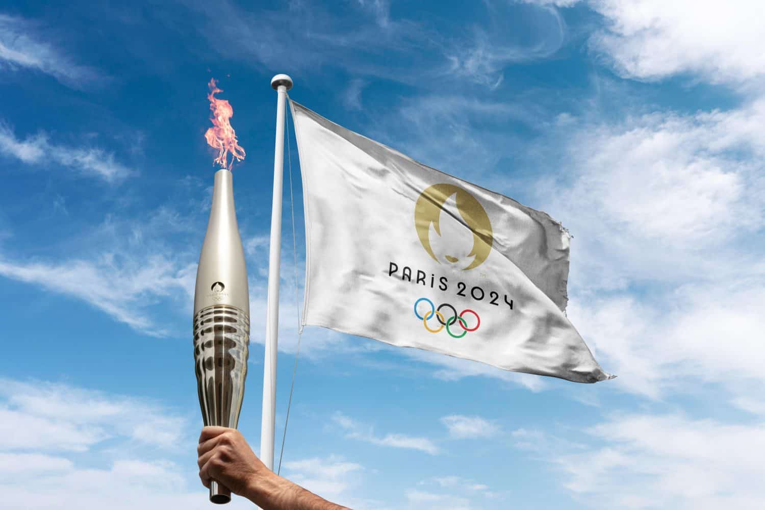 Paris 2024 Olympics flag waving at cloudy sky background. with the olympics flame holding by athlete.