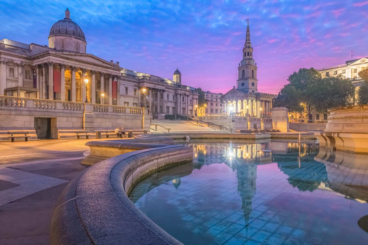 Night cityscape with a colourful, dramatic sky at sunrise or sunset at Trafalgar Square and the National Gallery in central London, UK.