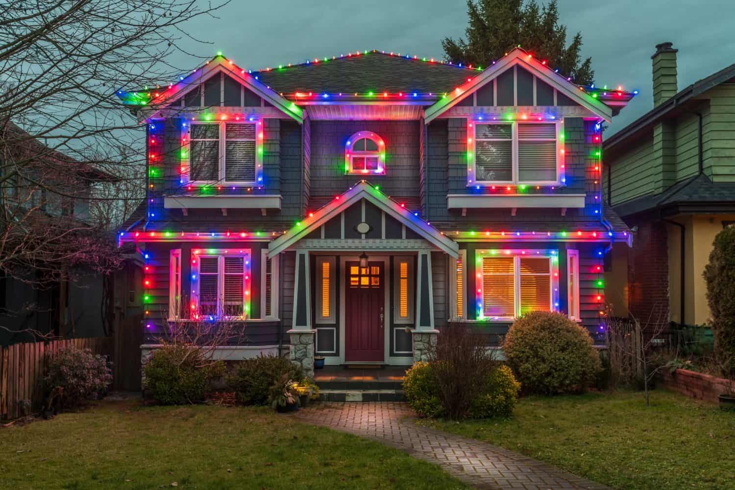 Two story stucco luxury house with garage door, big tree and nice Christmas decoration at night in Vancouver, Canada, North America. Night time on Dec 2021.