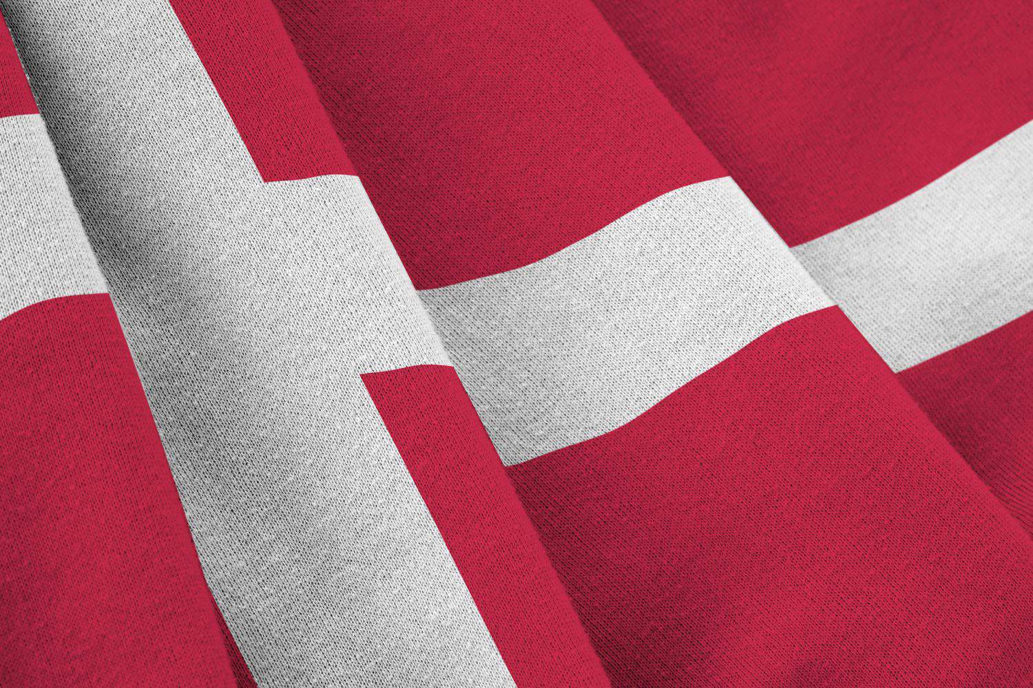 Denmark flag with big folds waving close up under the studio light indoors. The official symbols and colors in fabric banner