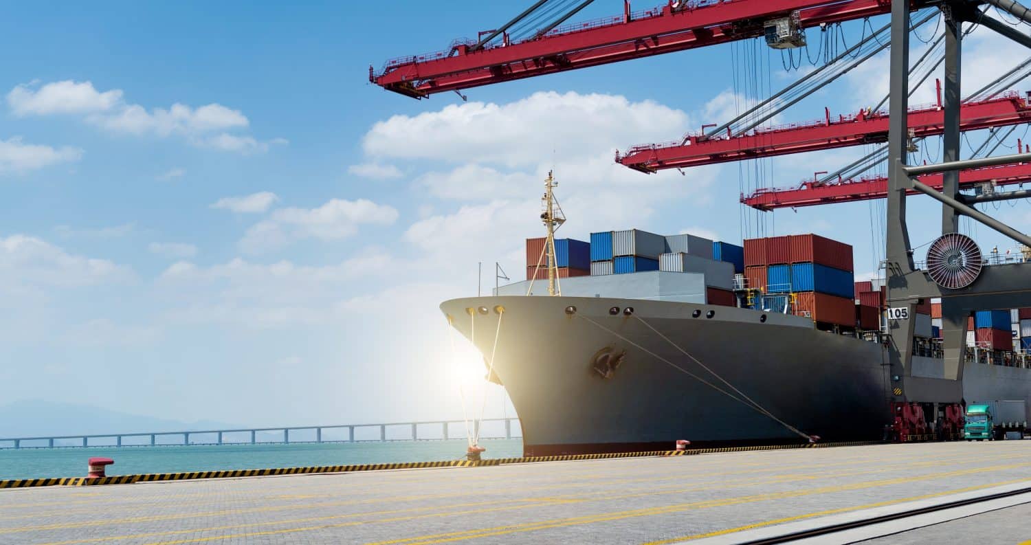 Container ship in the harbor with working crane bridge