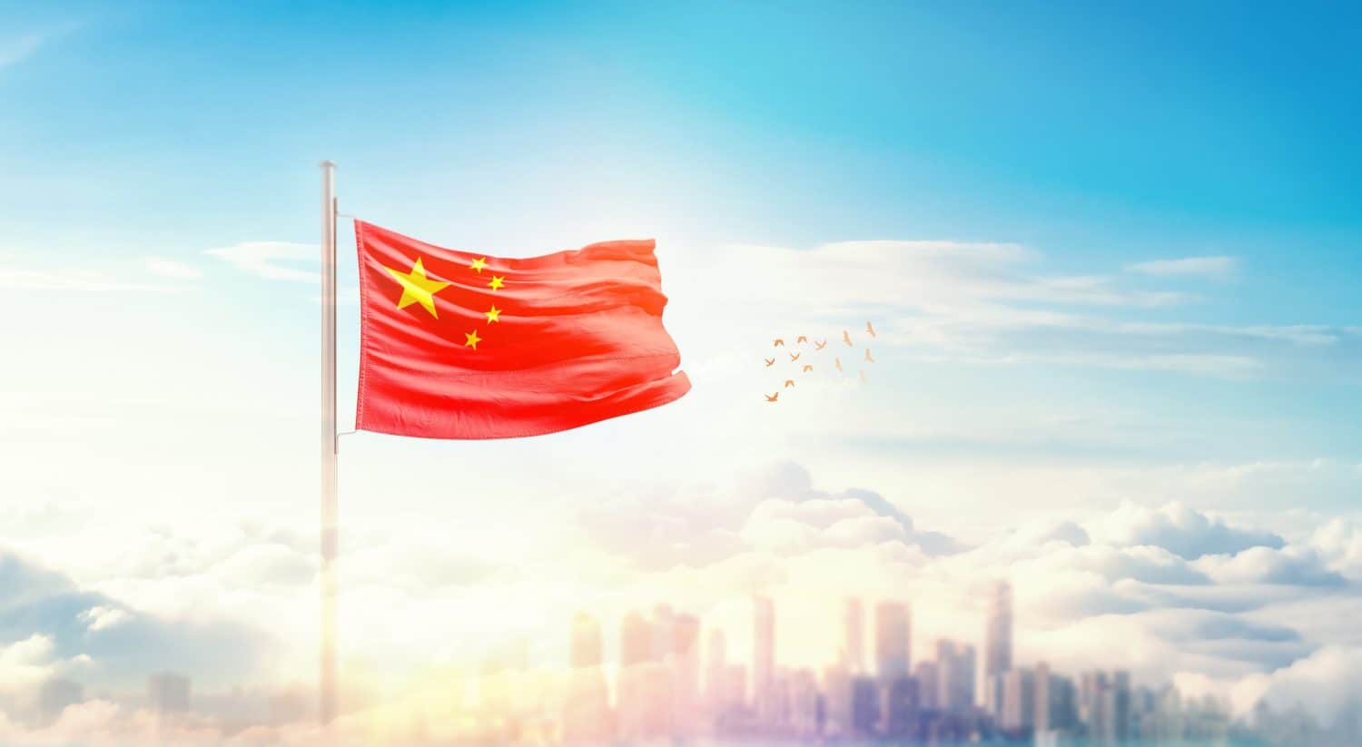 China flag wavering in beautiful clouds with building skyline. The flag with drone shot in beautiful sky. China national flag for independence day.