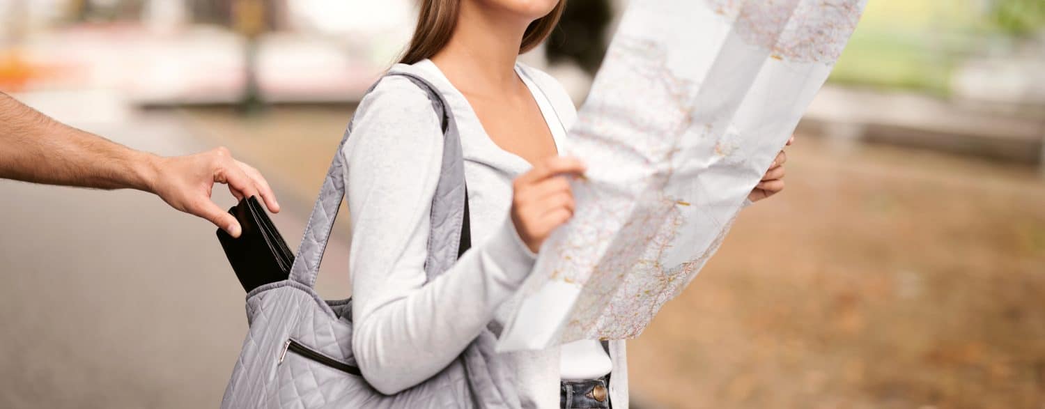 Travel And Pickpocketing. Thief Stealing Wallet From Tourist Girl&#039;s Bag While She Looking At Map Standing Outdoor. Cropped, Selective Focus