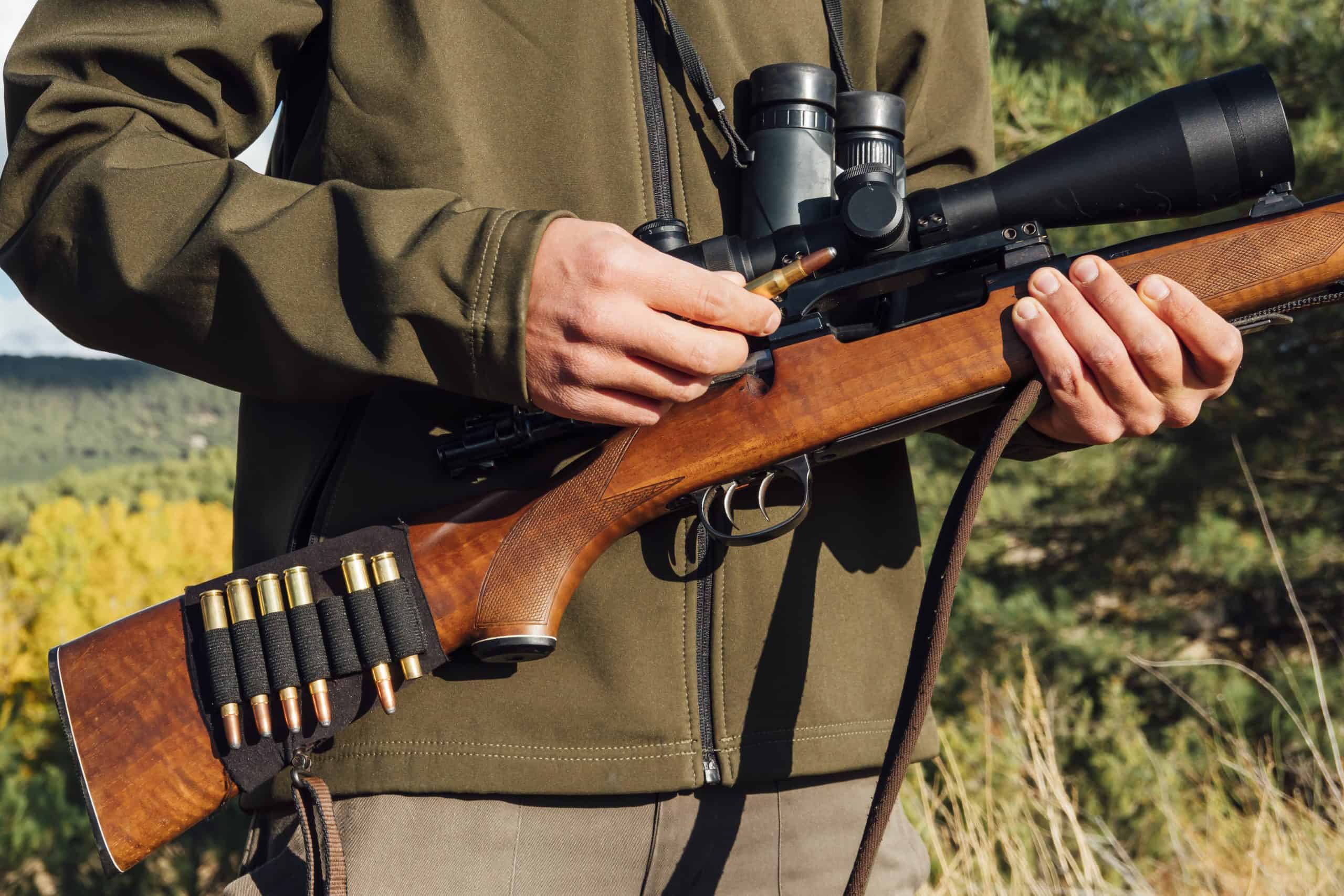 Hunter man on the mountain carrying the rifle with bullets