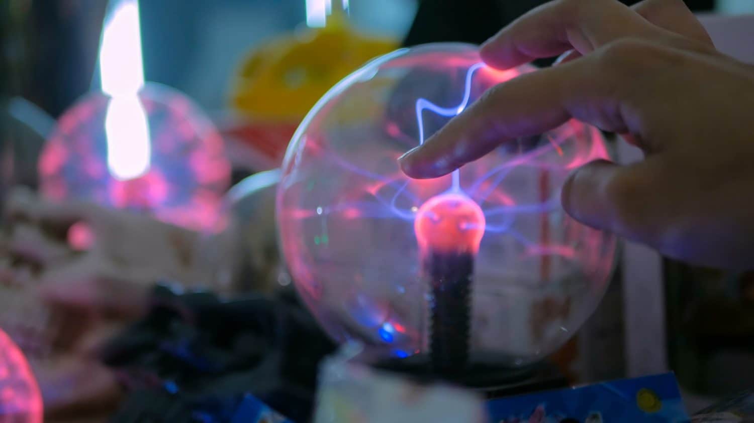 Woman hand touching plasma ball at technology exhibition. Physics concept