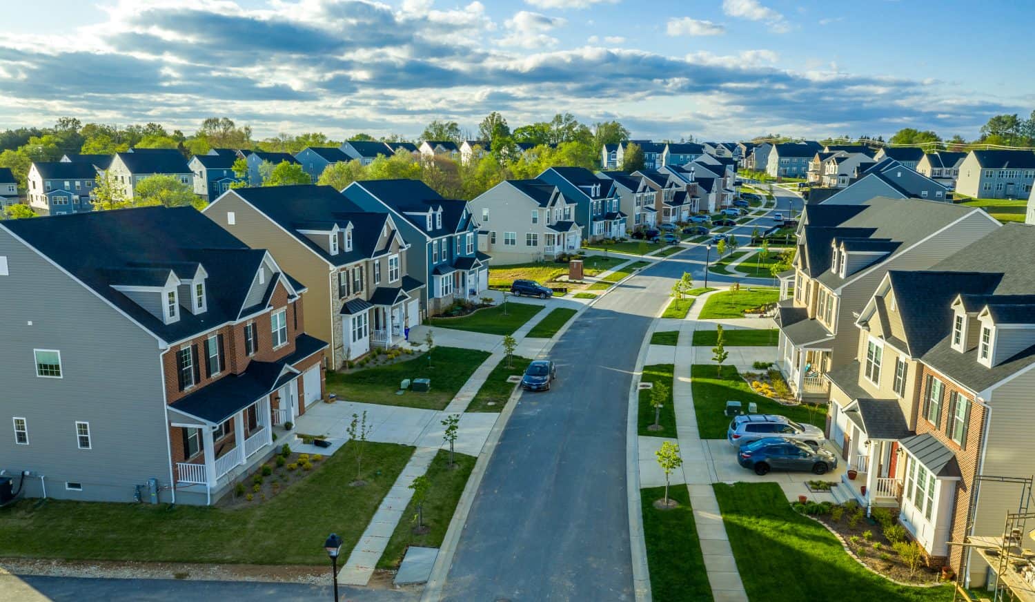 Aerial view of classic upper middle class neighborhood street with luxury single family homes with colorful siding for the up and coming with trees planted at equal distance in Maryland USA