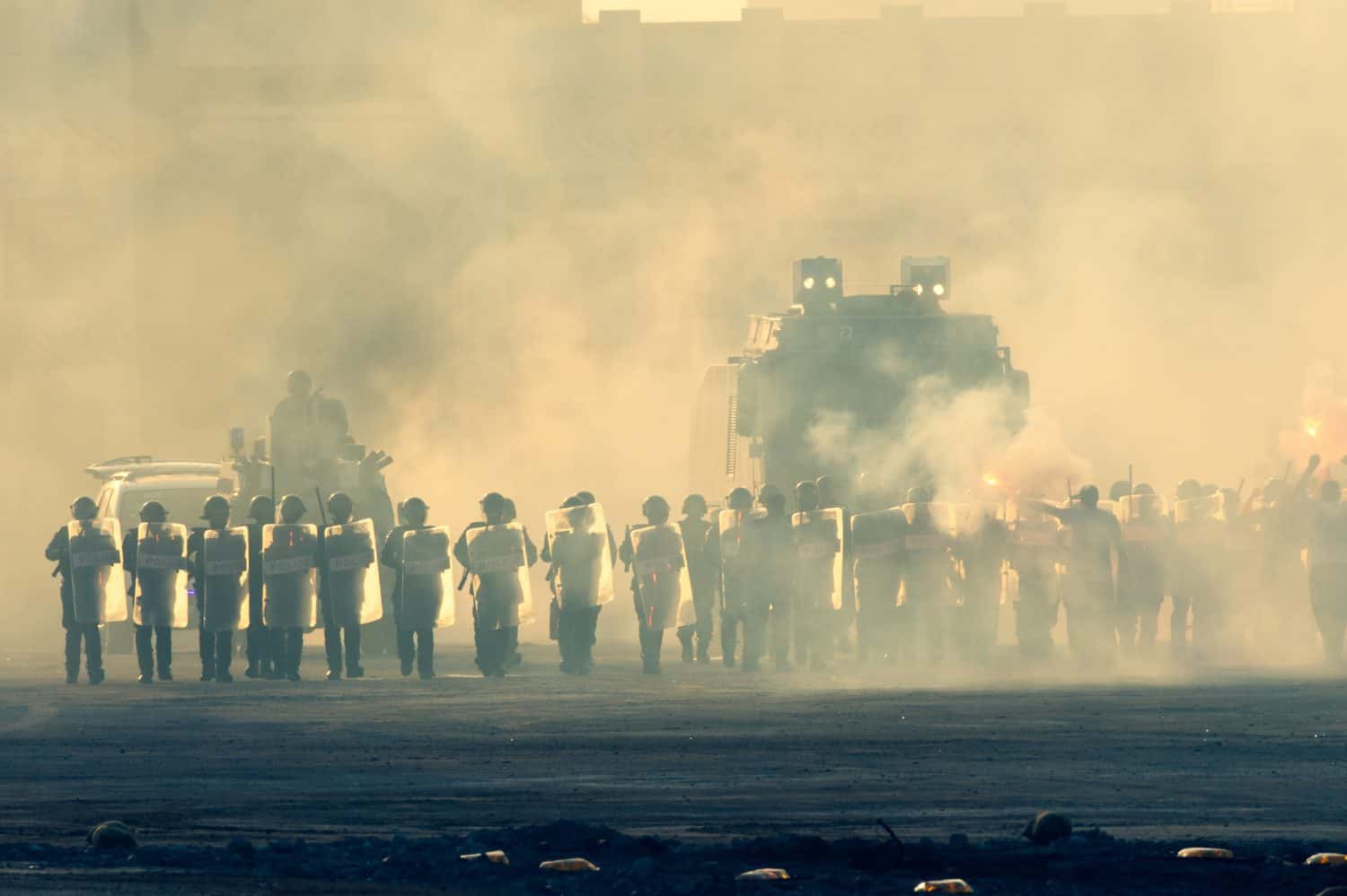 Military police riot response to a protest with tear gas, smoke, fire, explosions. Political expression, riot, protest, demostration and military concept.