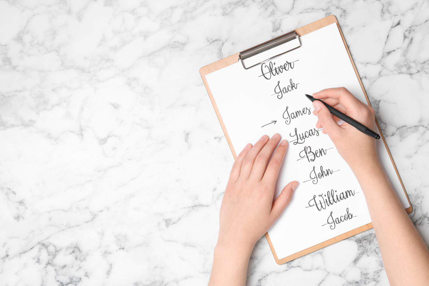 Woman choosing baby name at white marble table, top view. Space for text