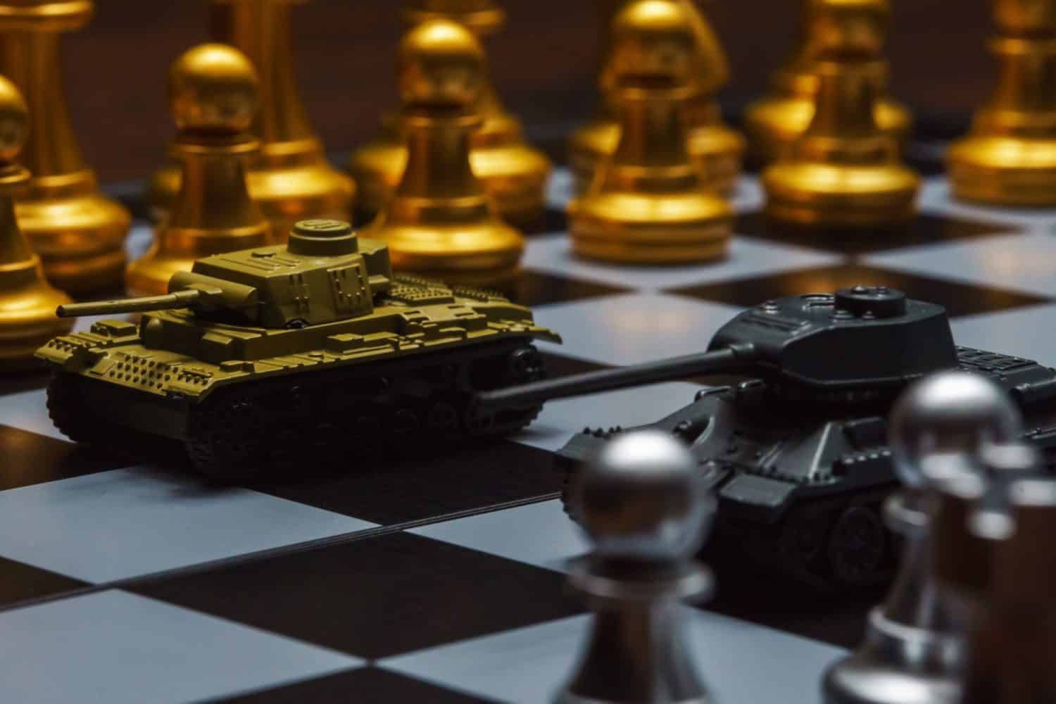 Toy tanks with chess on chessboard. Concept of military strategy.