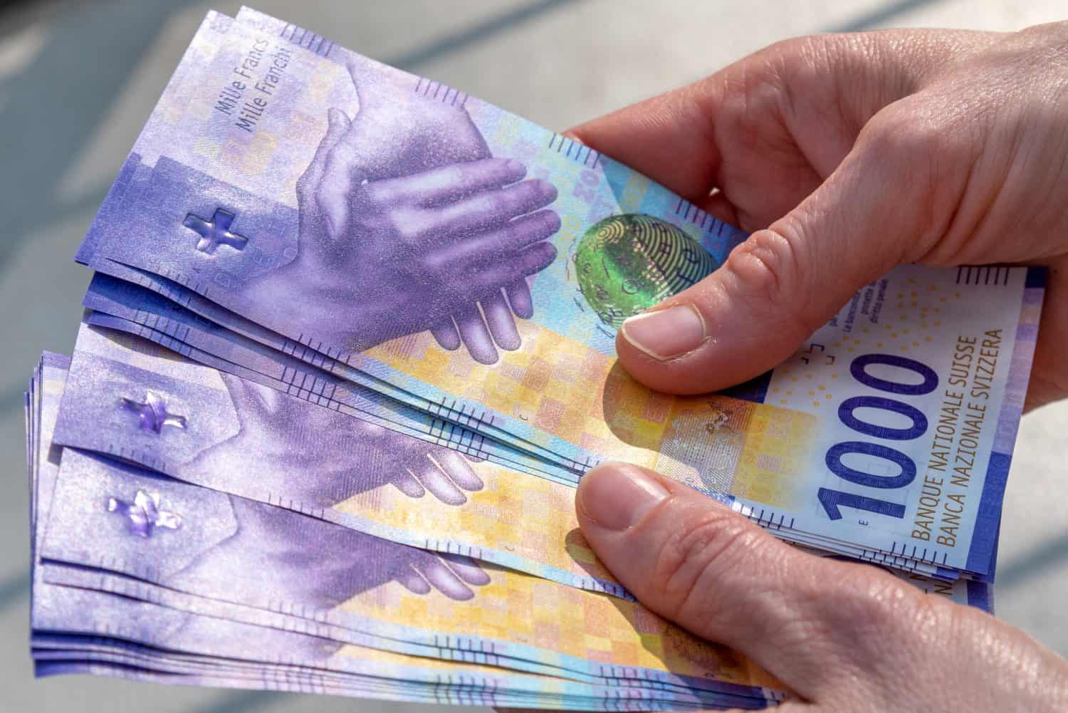 hands holding a stack of swiss francs money