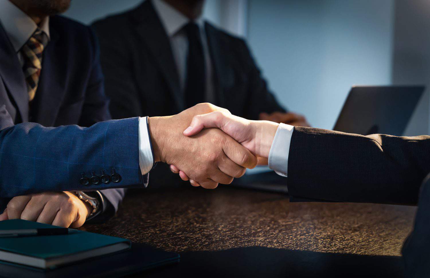 People shaking hands in a dark room. Corruption. Collusion.