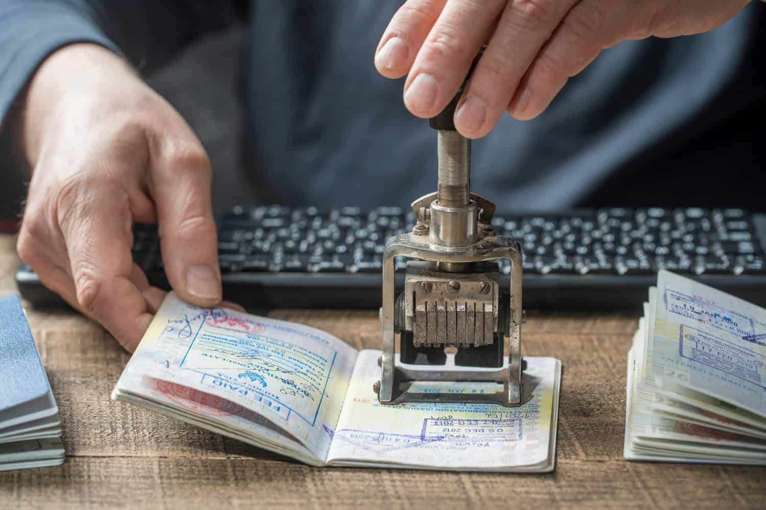 Immigration and passport control at the airport. Man border control officer puts a stamp in the international passport, close up. Vacation and travel concept