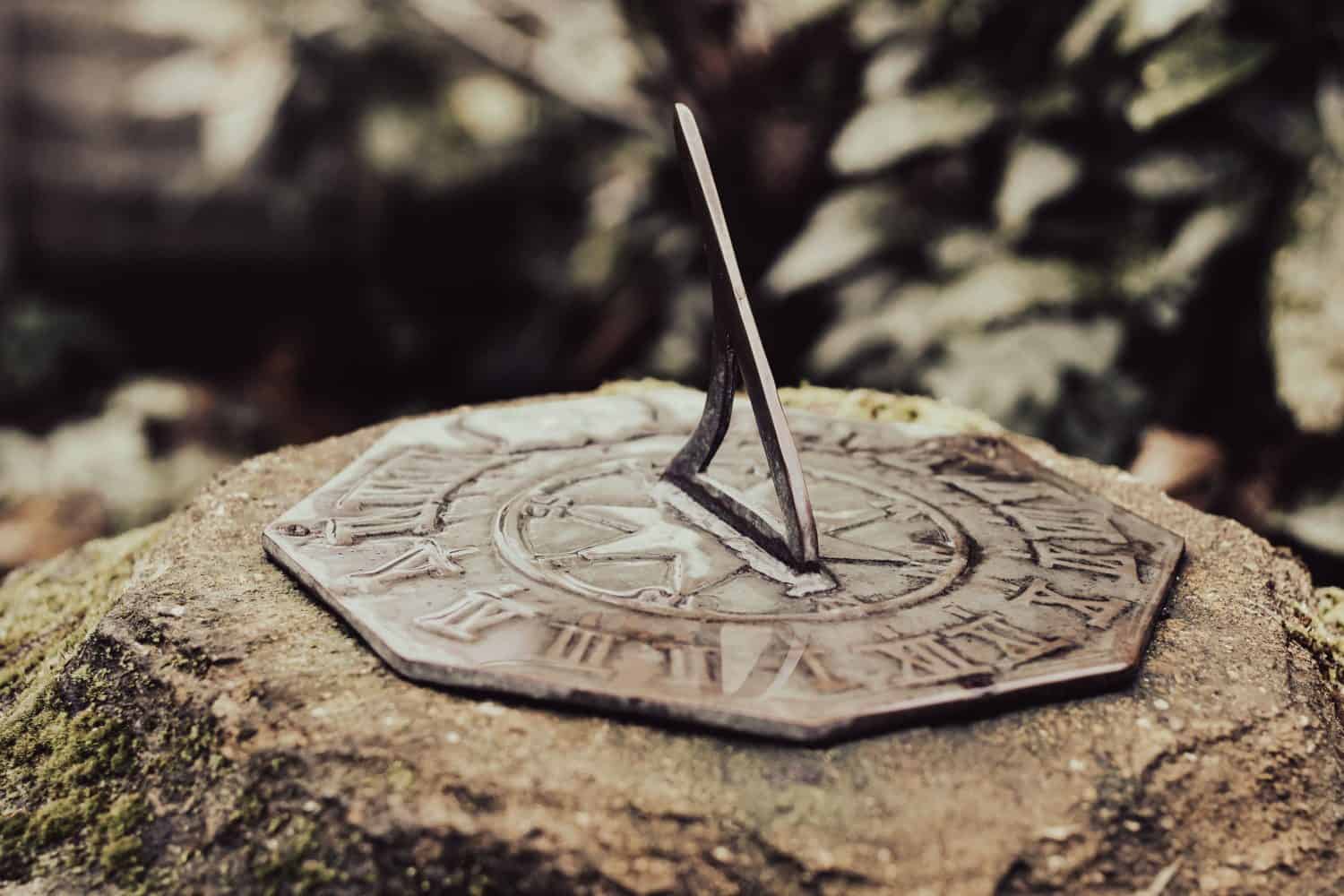 A closeup of a sunlit sundial set in a stone blurred background