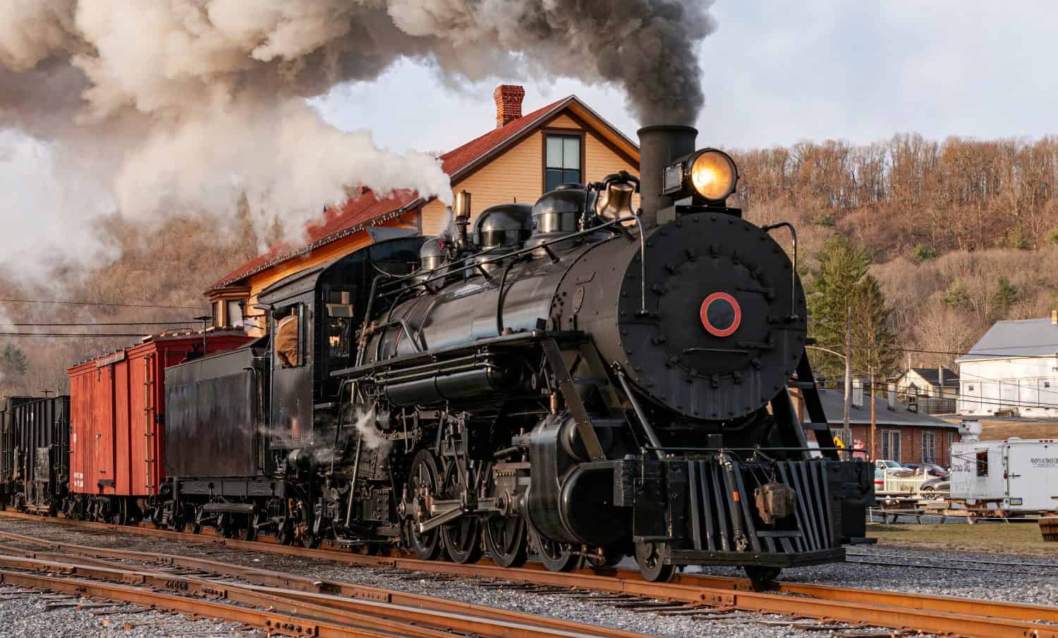 View of a Restored, Antique Steam Freight Train Approaching in Early Morning, on old Narrow Gauge Tracks on a Winter Day, Blowing Smoke