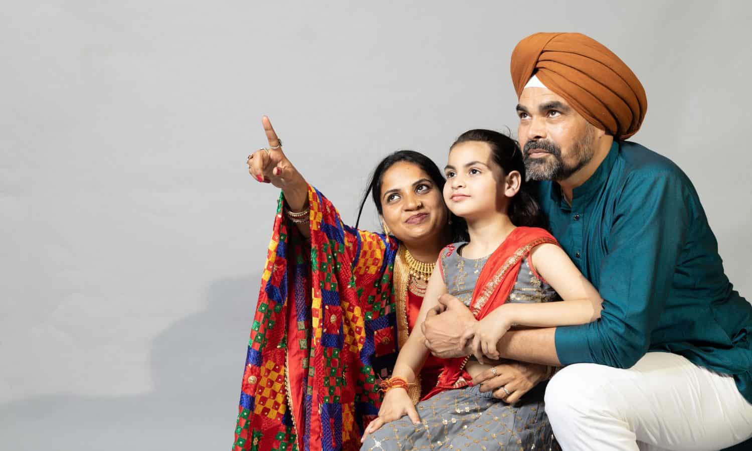 Portrait of Indian sikh Family together pointing towards the right .Lifestyle concept shoot of sikh family with copy space