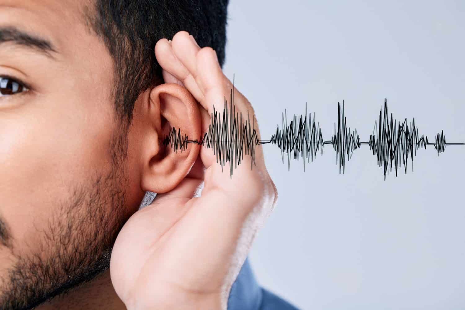 Ear, listening and sound waves with a hand on a studio background for communication, gossip or attention. Closeup, digital and a person for hearing an audio, speaker or frequency for conversation