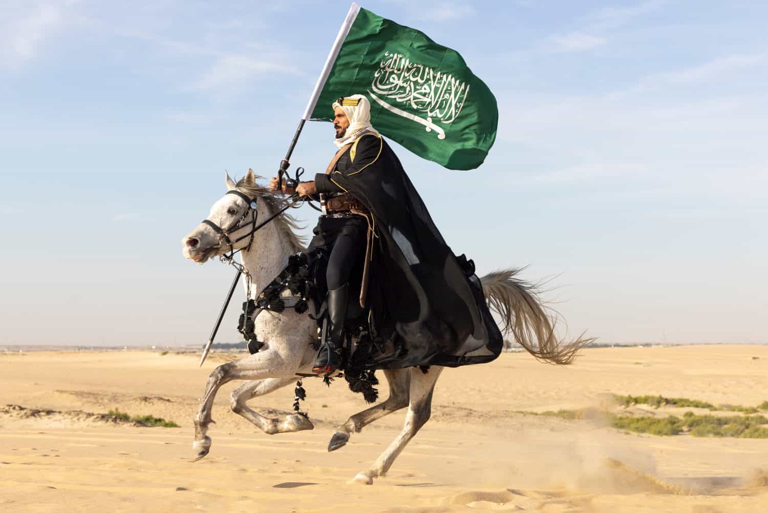 Man in traditional clothing with his horse in a desert