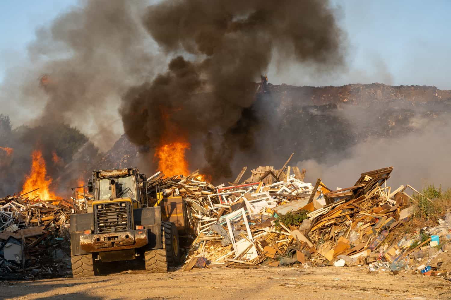 Garbage dump bulldozer pushing trash during a landfill fire