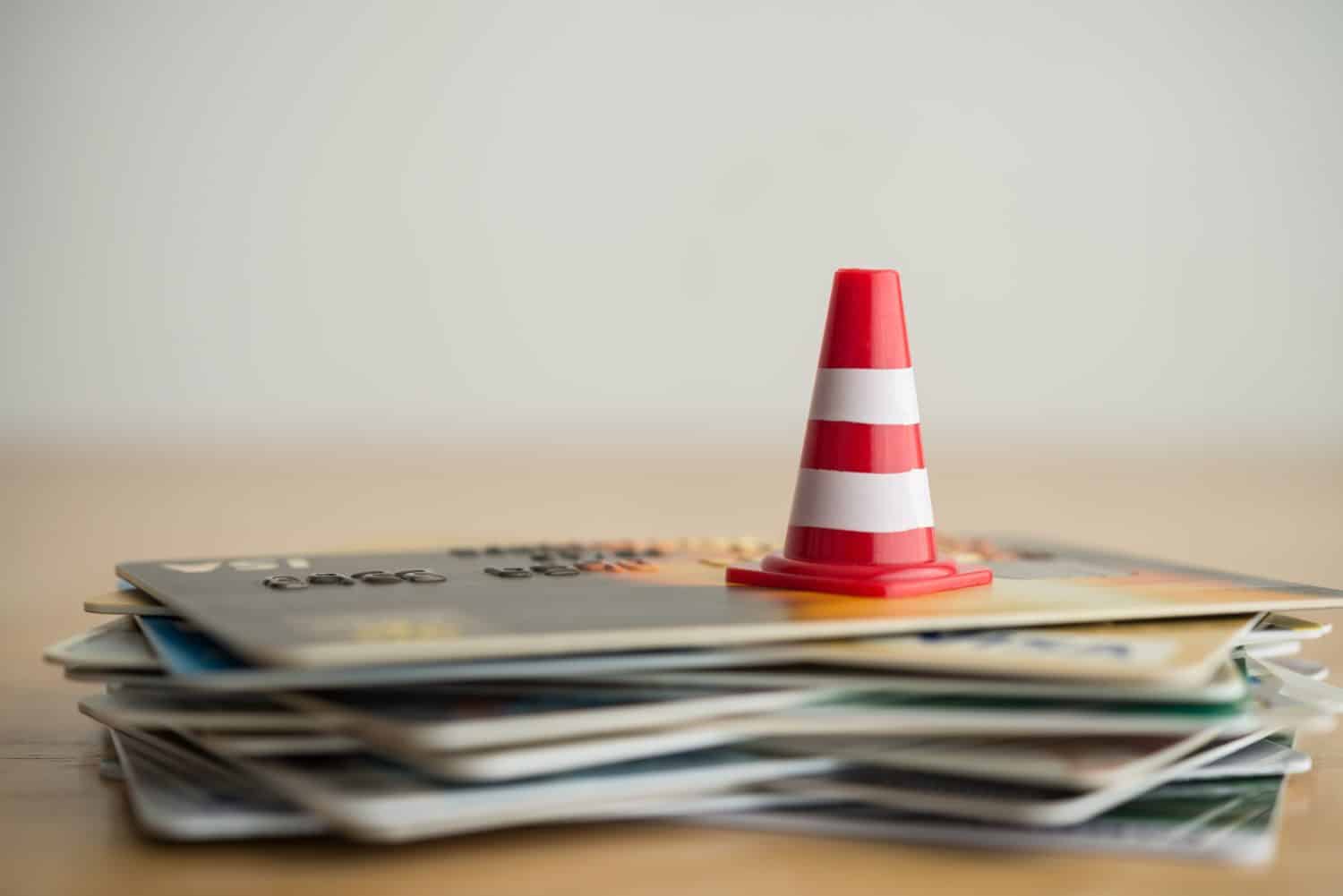 Close up red white traffic warning cones or pylon on many credit card white background. Past due payment or least minimum for credit card, personal financial problem, household debt issues concept.