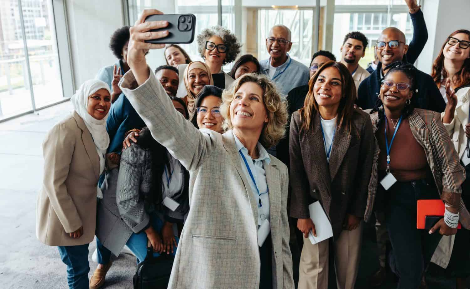 A diverse group of professionals taking a cheerful selfie together during a seminar or workshop. They are smiling and appear engaged.