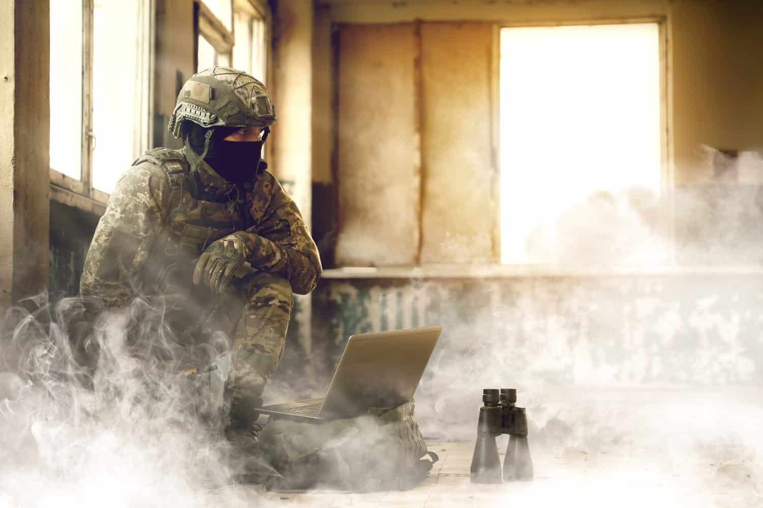 Soldier using laptop inside building during military operation