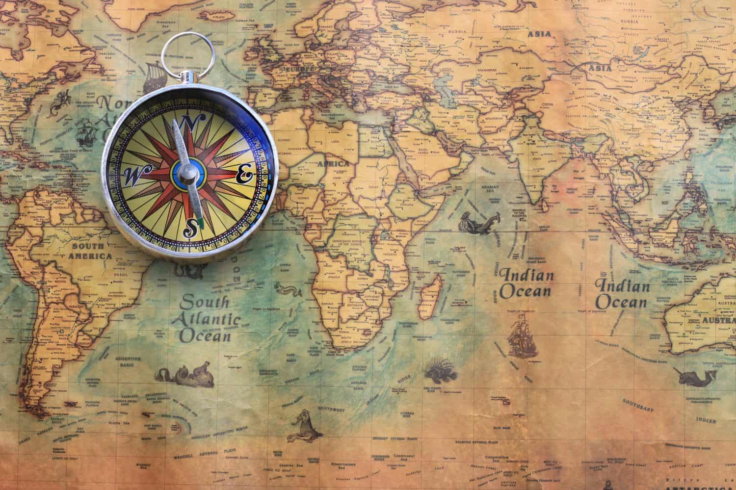 Classic round compass on background of old vintage map of world as symbol of tourism with compass, travel with compass and outdoor activities with compass