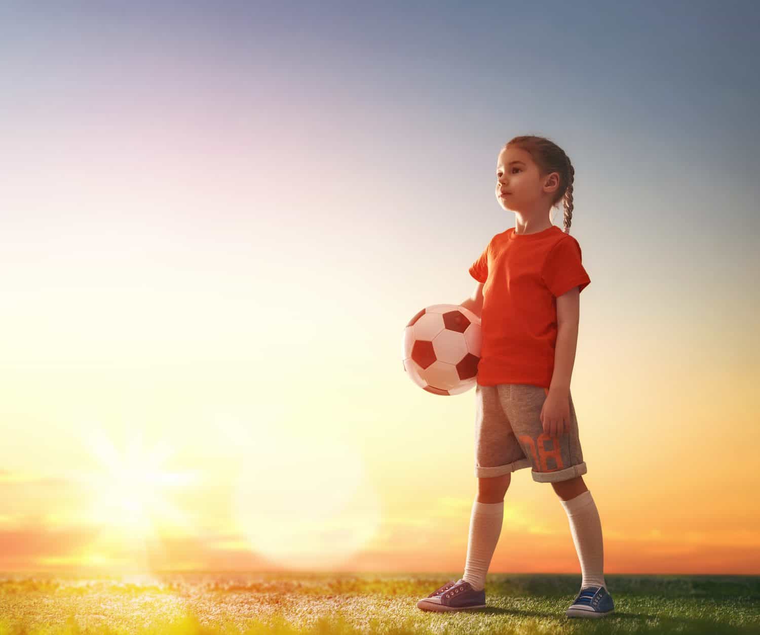 Cute little child dreams of becoming a soccer player. Girl plays football.