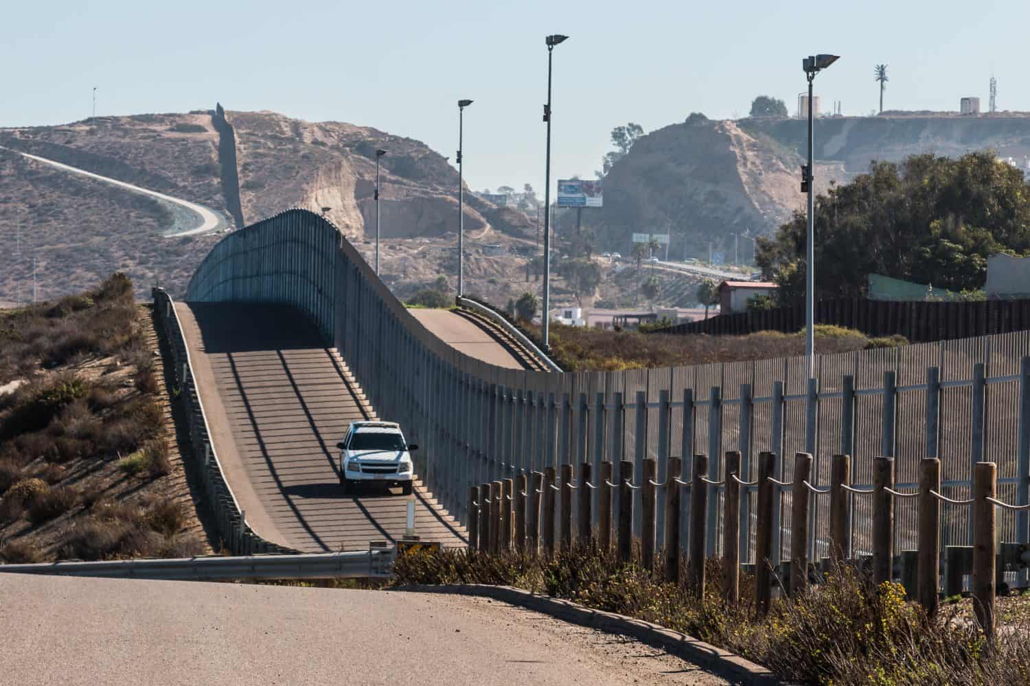 Border Patrol vehicle patrolling along the fence of the international border between San Diego, California and Tijuana, Mexico