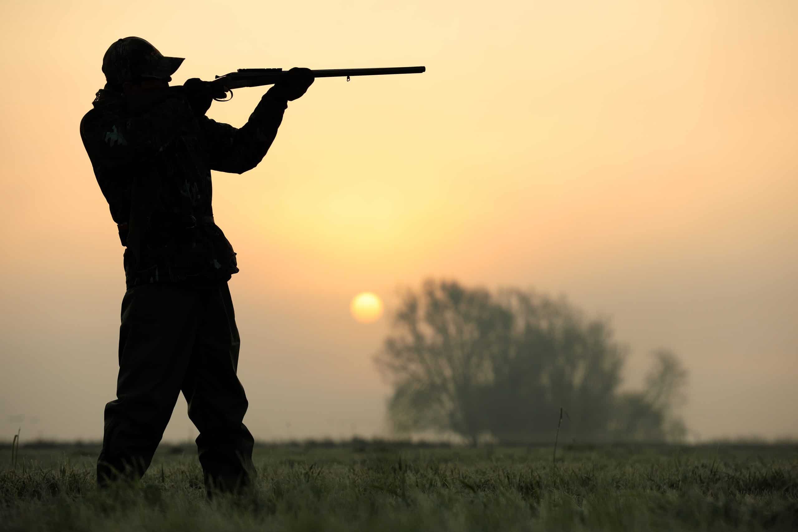 Silhouette of a hunter aiming his shotgun