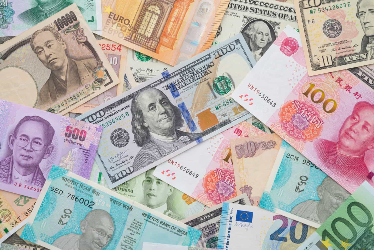 Flat lay or top view of world international banknotes vary countries background. US Dollar, Chinese yuan, Japanese yen, Euro, Indian rupee, Thai baht. Concept of Forex or global financial economic.